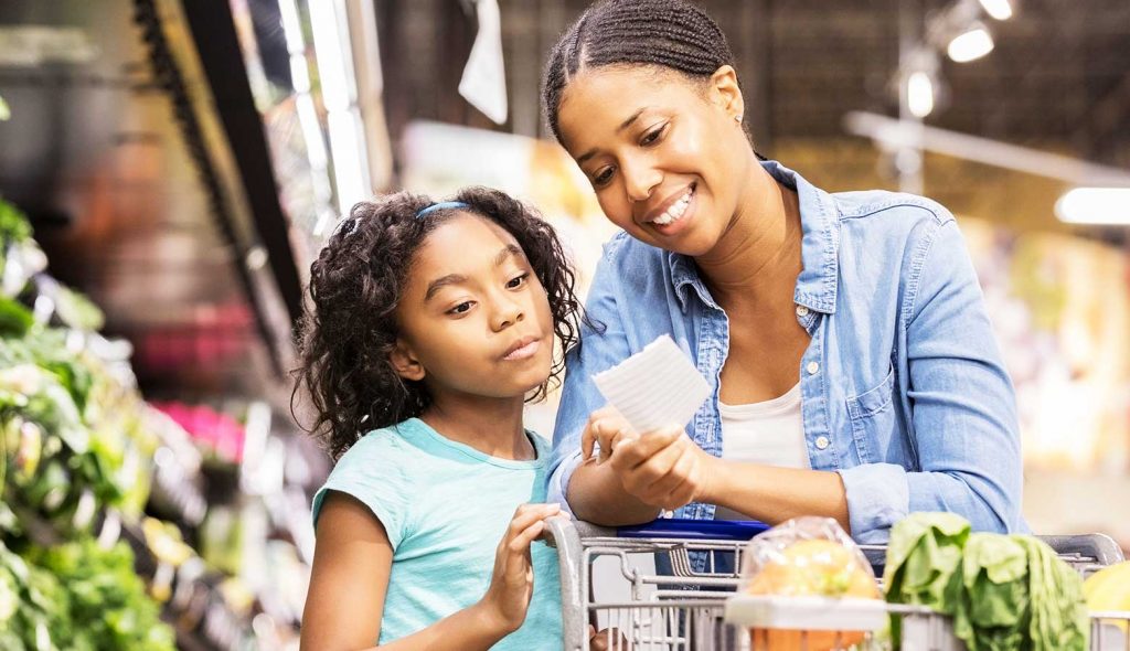 Mother and daughter reviewing their list while grocery shopping.
