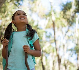 Little girl looking up in the trees on a nature trail hike.