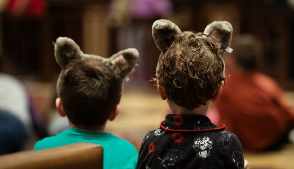 2 kids wearing wolf ears while listening to stories at a Great Wolf Resort.