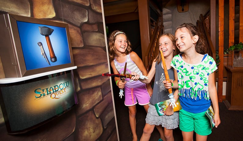 Girls playing with wand and pointing to sign reading shadow quest