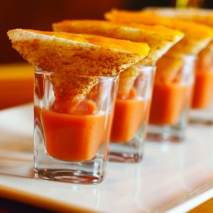 Mini grilled cheese shooters with tomato soup on white plate