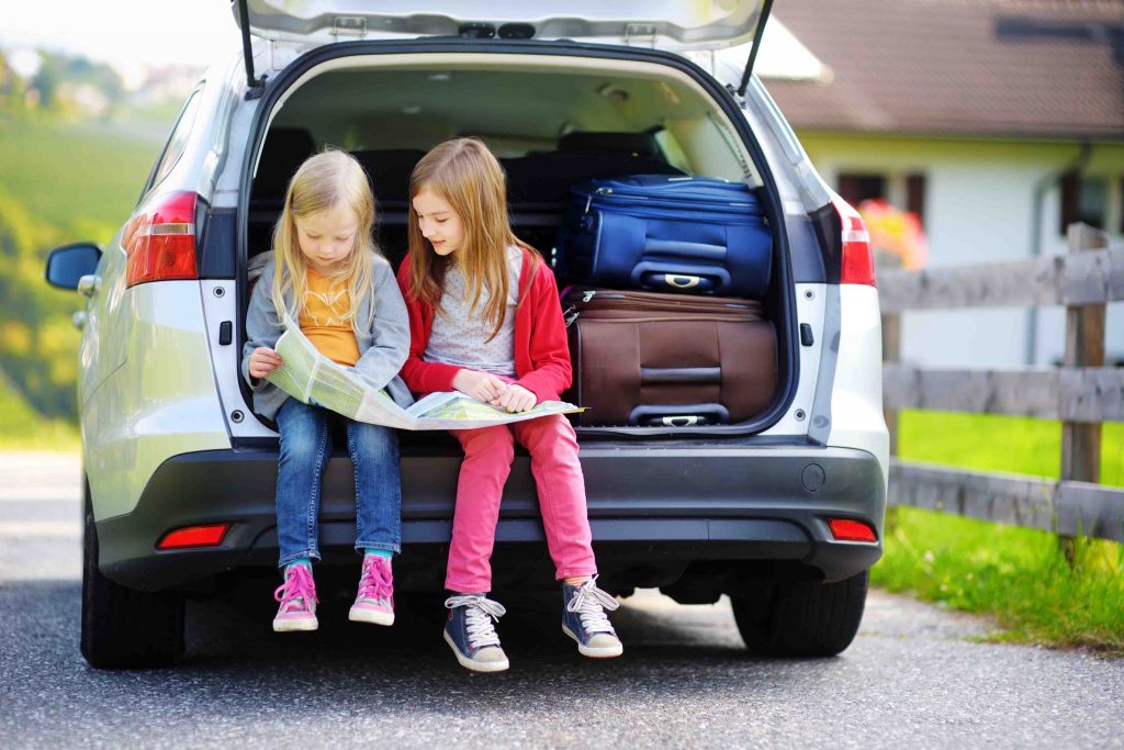 Two adorable little sisters exploring a map before going on vacations with their parents. Two kids looking forward for a road trip or travel.