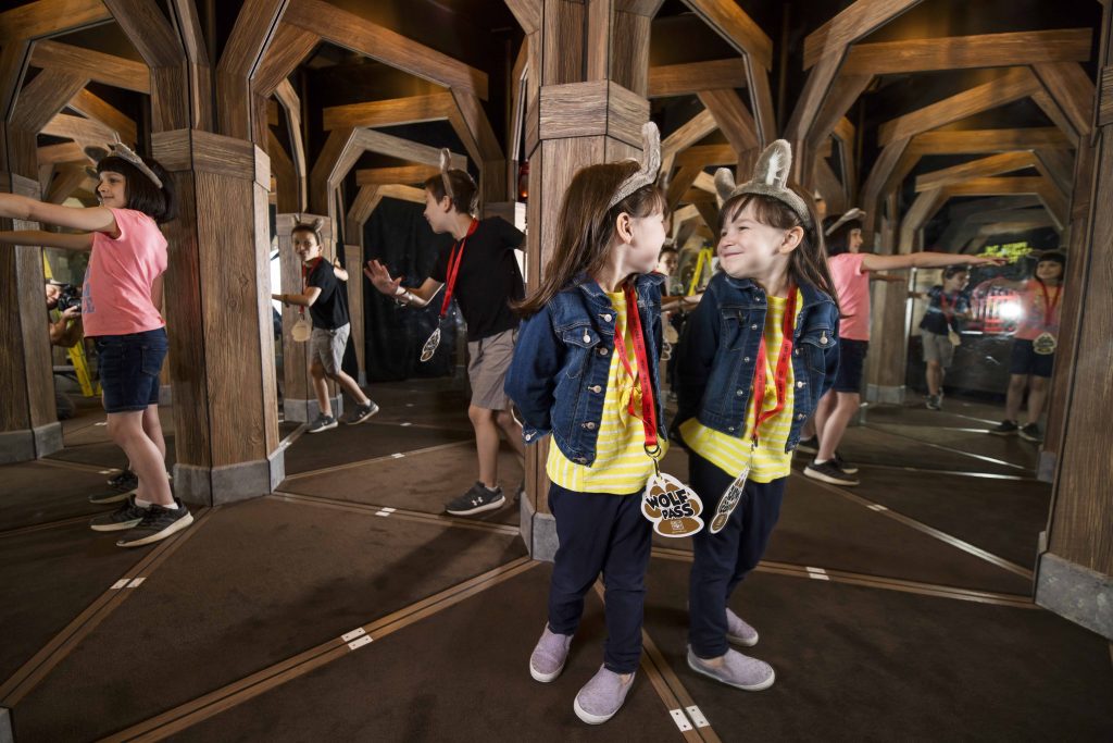 Little girl smiles at her reflection inside the mirror maze of Oliver's mining.