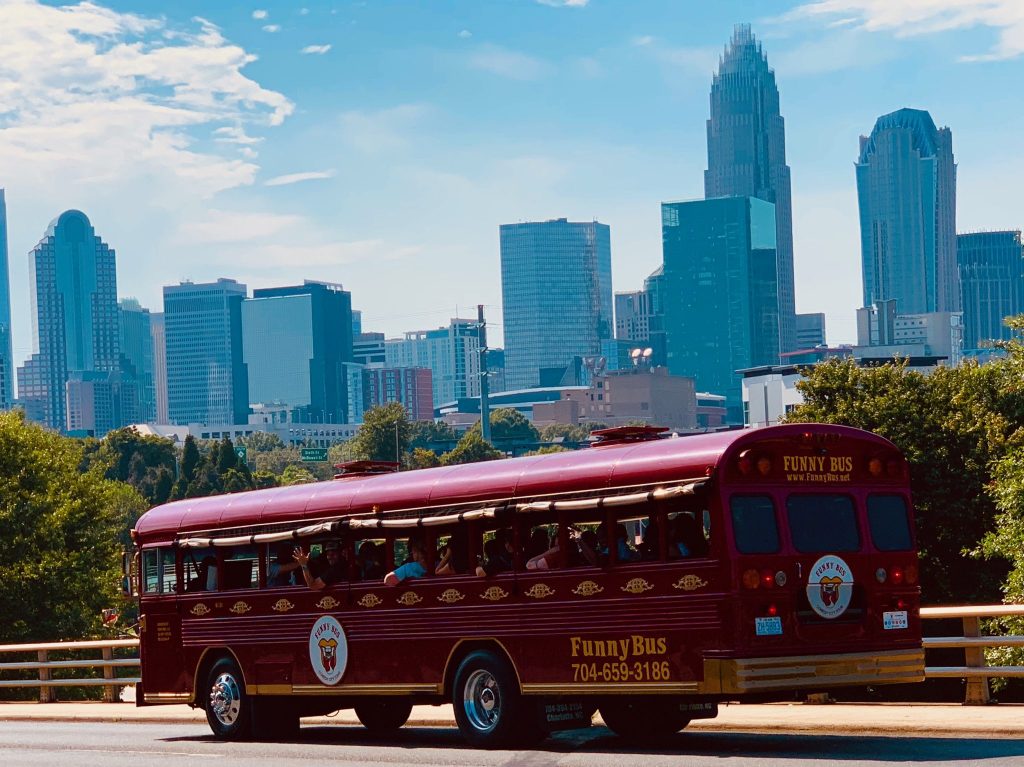 The red Funny Bus in Charlotte parked in front of the skyline